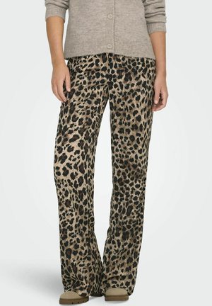 Pantalons larges en imprimé léopard avec une base beige et des taches noires et brunes. Tissu doux et coupe décontractée, associés à des chaussures neutres.