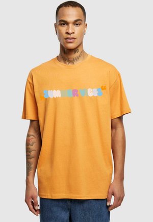 Orange bomulds T-shirt med et multifarvet "SUMMER VIBES" grafik over brystet. Korte ærmer, afslappet pasform og rund halsudskæring.