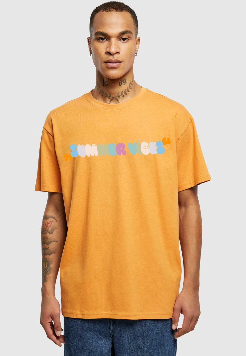 Orange bomulds T-shirt med et multifarvet "SUMMER VIBES" grafik over brystet. Korte ærmer, afslappet pasform og rund halsudskæring.