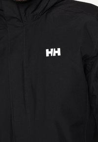 Veste imperméable noire avec capuche, texture lisse et un logo blanc "HH" bien visible sur le côté supérieur gauche.