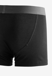 Schwarze Boxershorts mit einem grauen elastischen Bund, aus weichem, dehnbarem Stoff hergestellt. Verfügt über ein nahtloses Design und keine sichtbaren Muster.