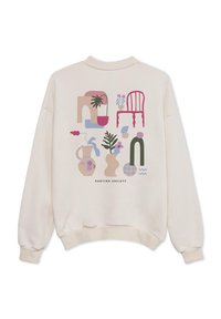 Κρεμ μπλούζα με έντονα, αφηρημένα γραφικά σχέδια φυτών, βάζων και μιας καρέκλας σε ροζ, πράσινους και μπλε τόνους.