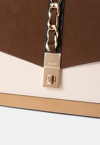 Brun, beige og hvit håndveske med glatte og teksturerte paneler, med et gullkjede som detalj og en metallisk lukking med merkenavnet ALDO.