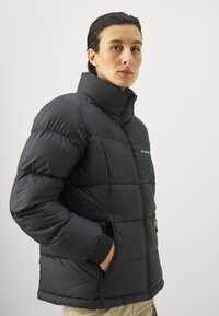 Czarna ocieplana kurtka puchowa z wysokim kołnierzem, poziomym pikowaniem, kieszeniami na zamek i elastycznymi mankietami dla pewnego dopasowania.