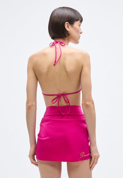 Rózsaszín pántos nyakú topp hátul megkötővel, hozzáillő szoknyával, amely sima textúrájú és hímzett logóval díszített.