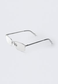 Óculos de metal com uma armação retangular e elegante. Acabamento em tom prateado com lentes transparentes e almofadas para o nariz. Hastes finas com extremidades arredondadas.