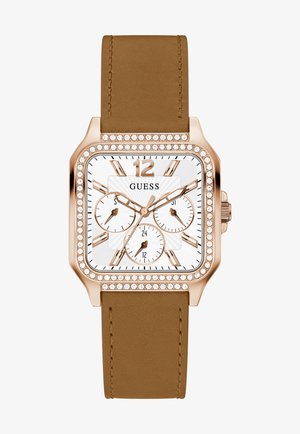 Kvadratni sat s ružičasto zlatnim kućištem, bijelim brojčanikom, tri podbrojčnika i kristalnim detaljima. Smeđa kožna narukvica s detaljima šivanja.