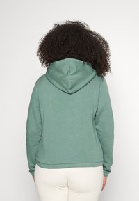 Mintgrön hoodie med dragsko i huvan, ribbad muddar och nederkant. Tillverkad av mjukt tyg med en slät yta och avslappnad passform.