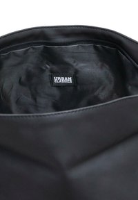 Musta kangaskassi sisemus sileäpintainen; varustettu vetskalla ja sisällä on valkoinen etiketti, jossa lukee "URBAN CLASSICS".