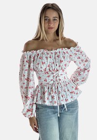 Weiße schulterfreie Bluse mit rotem Blumenmuster, gerafftem Ausschnitt, elastischem Bund und langen Puffärmeln, kombiniert mit hellblauen Jeans.