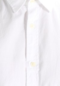 Biała koszula zapinana na guziki z klasycznym kołnierzykiem i żółtymi guzikami, wykonana z gładkiego materiału o minimalnej fakturze i bez wzorów.