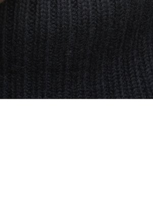 Gros plan sur la texture d'un tissu en maille côtelée noire avec de grosses boucles de fil créant des rayures verticales.