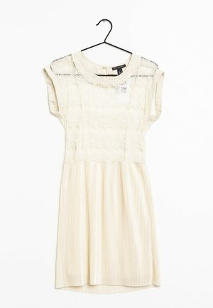 Kremowa sukienka z koronkową górą i spódnicą w paski. Posiada krótkie rękawy typu kaptur, okrągły dekolt i lekko zaokrąglony dół. Zawieszona na czarnym haczyku.