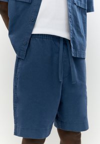 Shorts en coton bleu marine avec une taille élastique et un cordon de serrage, dotés de poches latérales et d'une coupe droite.
