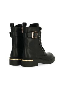Botas de tobillo de cuero negro con punta redondeada, tacón con detalles dorados, cordones en la parte delantera y correa ajustable con hebilla en el costado.