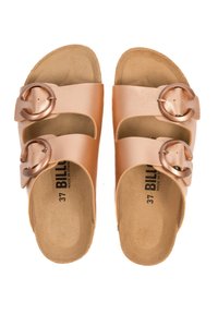 Sandales à glissière en rose doré avec deux larges sangles, chacune ornée d'une boucle en métal circulaire. Semelle douce de couleur caramel avec une texture minimaliste.