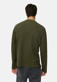 Olijfgroene shirt met lange mouwen, gemaakt van zachte stof. Heeft een ronde halslijn en een rechte zoom met zijsplitten.