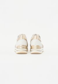 Sneaker con un design in materiali misti, caratterizzati da accenti crema e oro metallico, tacco strutturato e dettagli testurizzati sulla parte superiore.