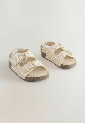 Sandały w panterkę z dwoma regulowanymi paskami, złotymi sprzączkami i beżową, teksturowaną cholewką. Gruba brązowa podeszwa na platformie z kropkami.