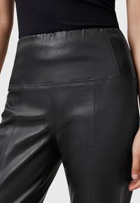 Black leather pants with a smooth texture, high elastic waistband, and tailored fit, featuring side seams and a sleek design.