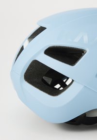 Casque de cyclisme bleu clair avec des fentes de ventilation et une surface intérieure texturée, vu en gros plan.