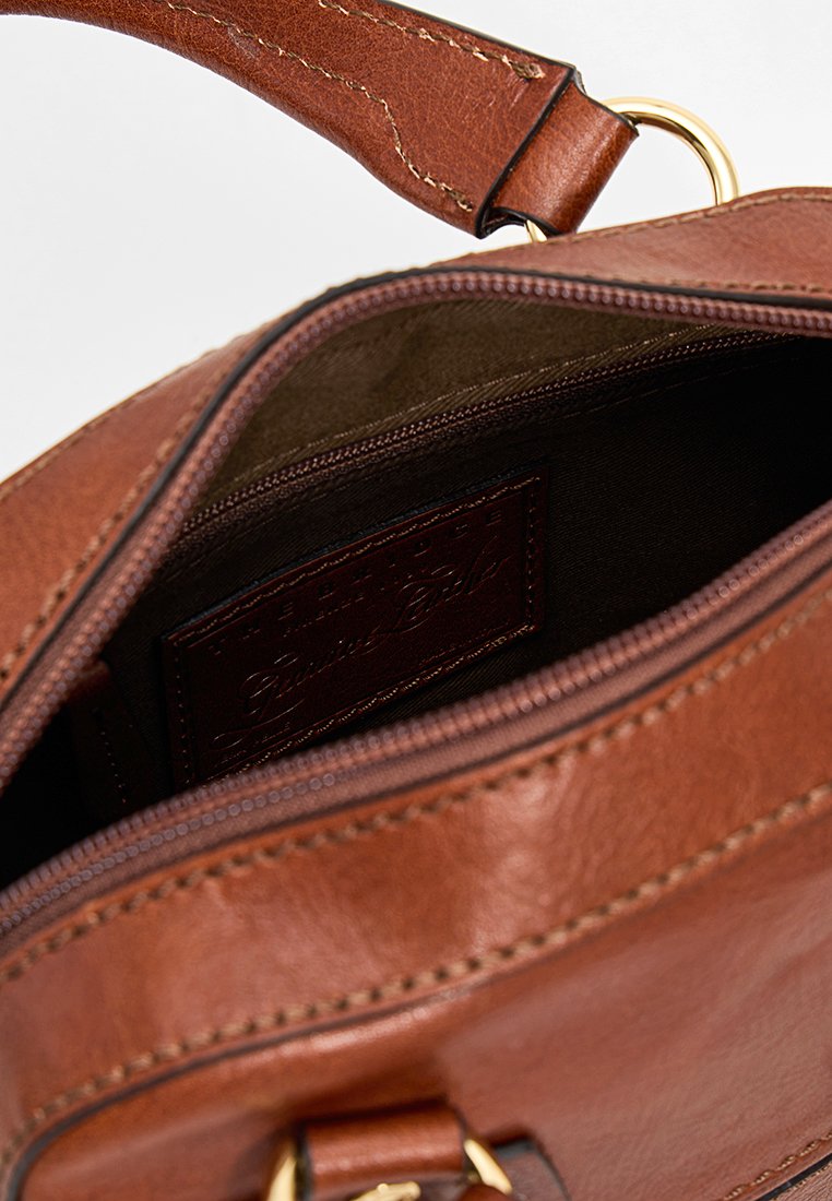 Braune Lederhandtasche mit Reißverschluss, goldenen Beschlägen und einer Innentasche. Besitzt sichtbare Nähte und eine strukturierte Oberfläche.