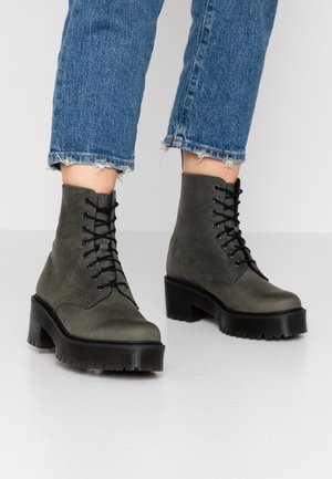 Ankelhøje sorte snørestøvler med tykke platformshæle, båret med korte blå denimjeans.