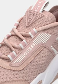 Ροζ πλεκτά αθλητικά παπούτσια με υφή επιφάνειας, διαθέτοντας λευκή λαστιχένια σόλα, κρεμ λεπτομέρειες και τριγωνικό λογότυπο από καμβά.