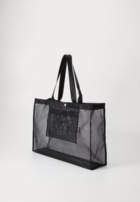 Black mesh tote bag with black fabric handles, rectangular shape, front pocket, and subtle logo detail. Lightweight, breathable material.