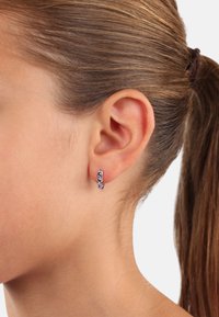 Orecchino a cerchio in argento con numerosi piccoli gemme viola disposte in un motivo lineare. Finitura in metallo liscia e lucida, design leggero.
