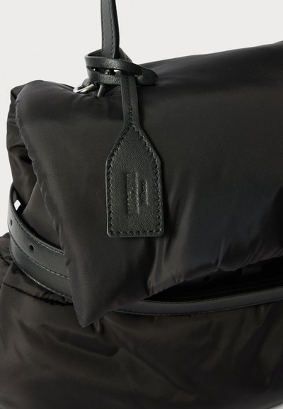 Μαύρη νάιλον τσάντα χειρός με λείο, επενδεδυμένο εξωτερικό, λεπτομέρεια από δερμάτινη λωρίδα και ορθογώνια δερμάτινη ετικέτα με ανάγλυφα λογότυπα.