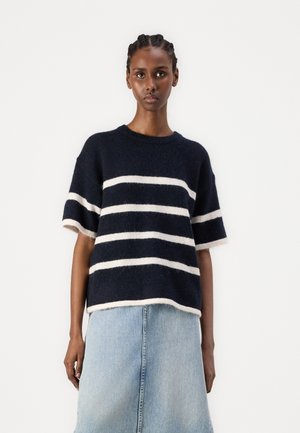 Maglione a righe navy realizzato in materiale morbido con righe orizzontali crema. Maniche corte e scollo rotondo, abbinato a una gonna di jeans chiara.