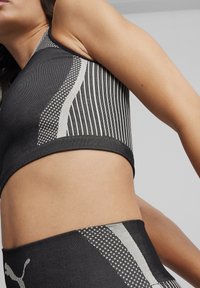 Sort og hvid sports-bh med lodrette og skrå stribemønstre, der har en tætsiddende pasform og struktureret stof. Følger med matchende leggings.