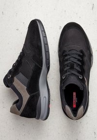 Černé sportovní boty z semiše a síťoviny s šedým akcentním panelem, texturovaným jazykem a gumovou podrážkou s červenými detaily.
