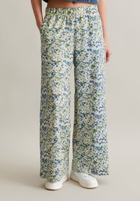 Floral wide-leg pants in light fabric with green and blue patterns, an elastic waistband, and side pockets. Paired with white sneakers.