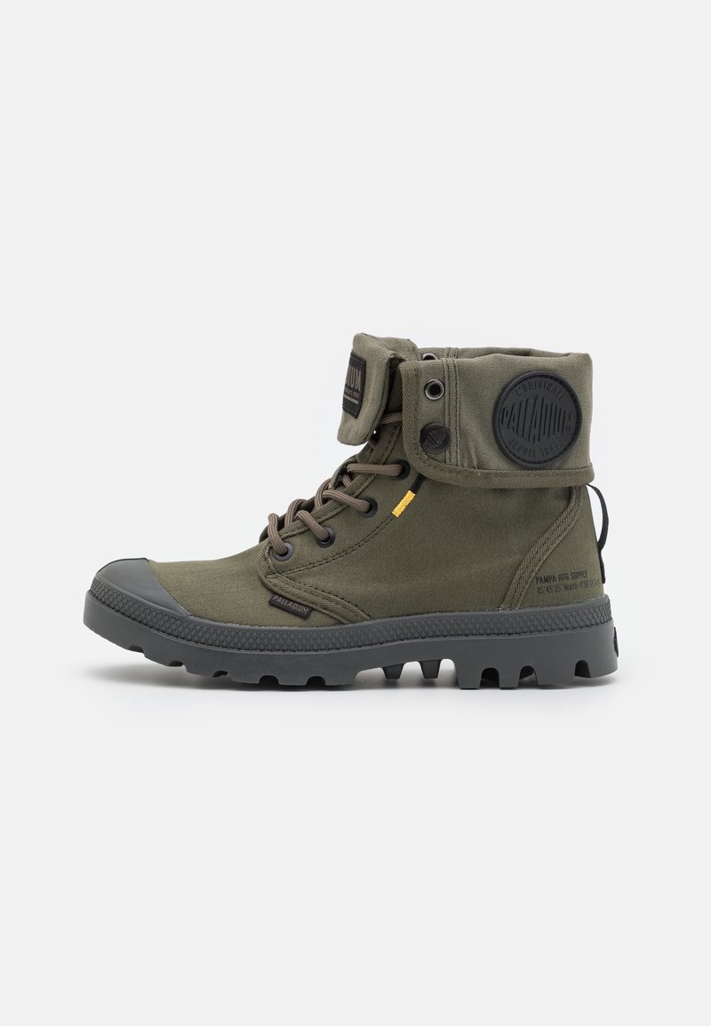 Botte montante en toile vert olive avec semelle en caoutchouc noir, lacets, revers pliant et patch logo circulaire sur le côté.