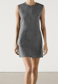 Robe grise sans manches avec une silhouette cintrée, réalisée en tissu lisse, présentant un design minimaliste et de subtils détails de couture.