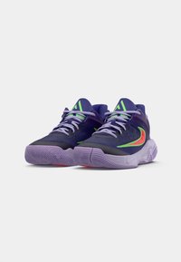 Pár fialových basketbalových bot s neonově zeleným a červeným logo Nike, světle fialové podrážky a odpovídající tkaničky na bílém pozadí.
