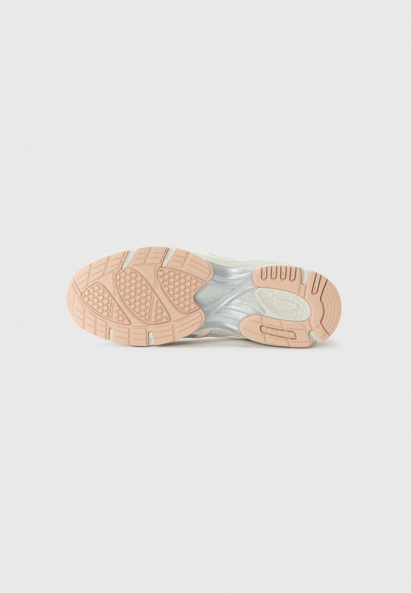 Suela de zapatilla en tonos beige y blanco con patrones de tracción de goma texturizada y una entresuela translúcida. Los acentos incluyen formas redondeadas y surcos.
