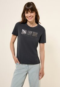 Mörkgrå t-shirt med korta ärmar, med en metallisk djurtrycksgrafik och text. Mjukt tyg med avslappnad passform.
