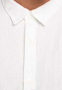 Witte linnen shirt met een zachte textuur, voorzien van een klassieke kraag, knoopsluiting aan de voorkant en semi-doorzichtige stof.
