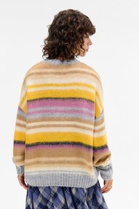 Maglione a righe multicolore con morbida texture in maglia. I colori includono giallo, rosa, grigio e beige, con scollatura rotonda e vestibilità ampia.