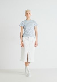 Lyseblå og hvitstripet kortermet skjorte kombinert med et hvitt denimskjørt til kneet med et frontslitt og hvite sneakers.
