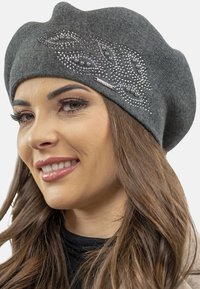 Beret din lână gri, cu un model decorativ de frunze din strasuri și accente metalice. Textură moale, formă rotundă și croială lejeră pentru confort.