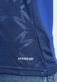 T-shirt de sport bleu marine avec un motif texturé, logo Aeroready en blanc et un panneau en tissu contrastant avec une finition lisse.