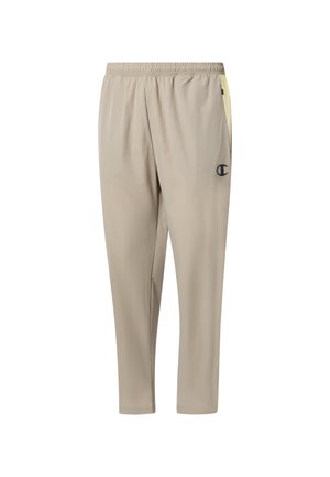Beżowe sportowe spodnie z elastycznym pasem, zwężanymi nogawkami, bocznymi kieszeniami oraz małym czarnym logo na prawej udzie.