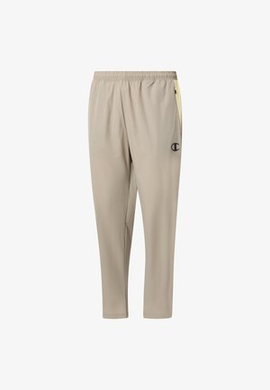 Pantaloni sportivi beige con fascia elastica in vita, gambe affusolate, tasche laterali e un piccolo logo nero sulla coscia destra.