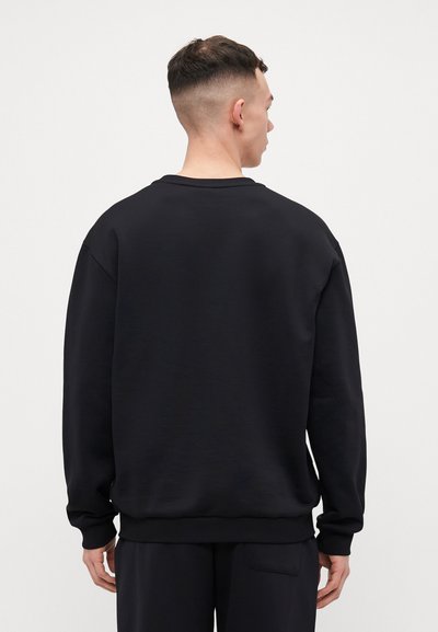 Black crewneck sweatshirt, relaxed fit, ribbed collar and cuffs, soft texture, minimal design, no visible logos or patterns.