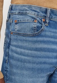 Lyseblå denimjeans har en klassisk fem-lommersdesign, med kobberdetaljer og søm, en lett falming og en tettsittende silhuett.