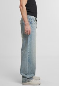 Jeans in denim azzurro chiaro, dalla vestibilità ampia e design a gamba dritta, con classici taschini e leggera sbiaditura. Abbinati a sneakers bianche.